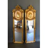 A pair fo French style gilded dressing mirrors, each with a scroll cresting above a relief moulded