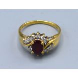 An 18ct gold ring set with an oval ruby surrounded by diamonds, claw set, ring size P, 3.1g