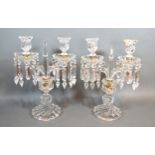 A pair of cut glass two branch candelabrum with facet cut glass drops, 33cms tall