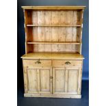 A Pine Dresser, the boarded shelf back above two drawers with brass cup handles above two panelled