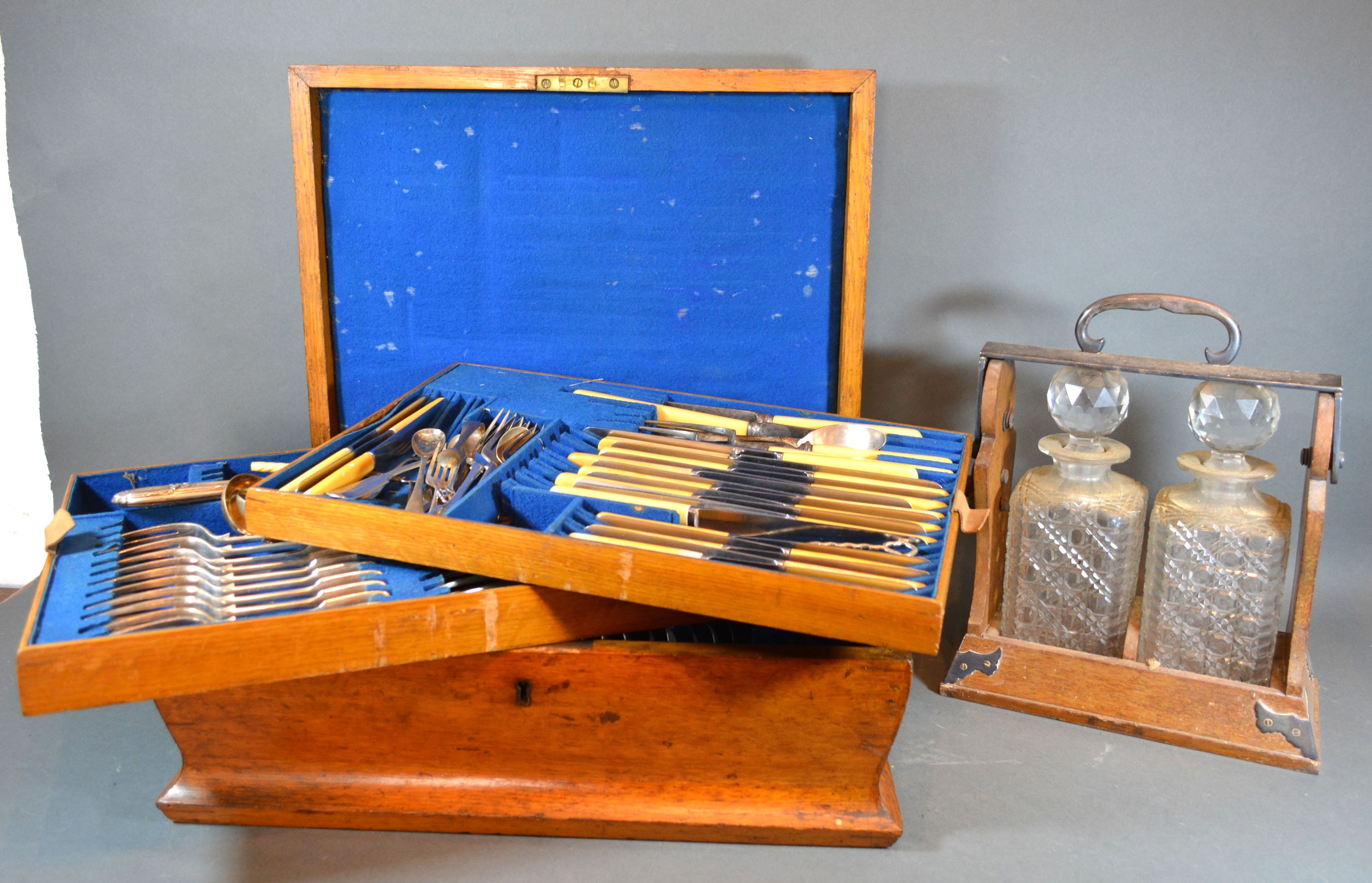 A Silver Plated Canteen of Cutlery housed within an oak canteen cabinet together with a tantalus