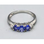 An 18ct. White Gold Tanzanite and Diamond Ring set with three tanzanite flanked by small diamonds,