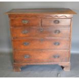 An 18th Century Oak Chest, the plank top above a shaped frieze and two short and three long