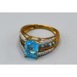 A 9ct. Gold Dress Ring set with a central rectangular blue stone with diamond shoulders, ring size