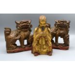A Chinese Gilded Figure 18 cms tall together with a pair of Chinese carved dogs of fo, 16 cms tall