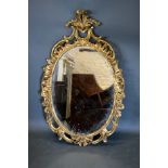 A French Gilt Wood Wall Mirror of oval form with a pierced scroll cresting, 108 x 69 cms