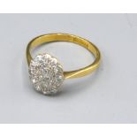 An 18ct. Gold and Platinum Diamond Set Cluster Ring of oval form, ring size M, 2.6 gms.