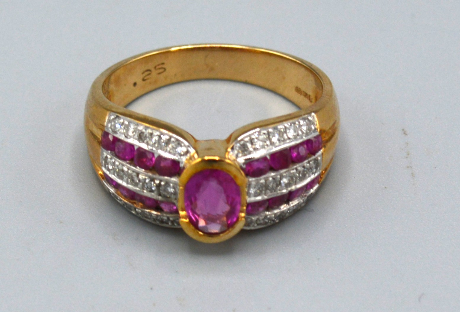 A 9ct. Gold Ruby and Diamond Ring with central oval ruby flanked by bands of rubies and diamonds,