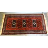 A Bokhara Woollen Rug with three medallions within an all over design upon a red blue and cream