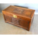 A Chinese Hardwood Trunk, the hinged cover above a carved front with brass lock, 104 cms wide, 53.