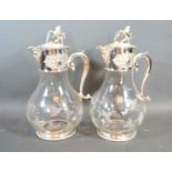 A pair of silver plated and engraved glass claret jugs, each engraved with grape vine, the covers
