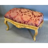 A French Style Large Gilded Stool, the burgundy upholstered top above a carved frieze raised upon