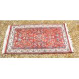 A North West Persian small rug with an all over design upon a red, blue and cream ground within