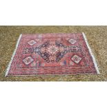 A North West Persian woollen rug with a central medallion within an all over design upon a red, blue