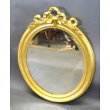 A Late 19th Early 20th Century French Oval Gilded Wall Mirror with bow cresting and bevelled glass