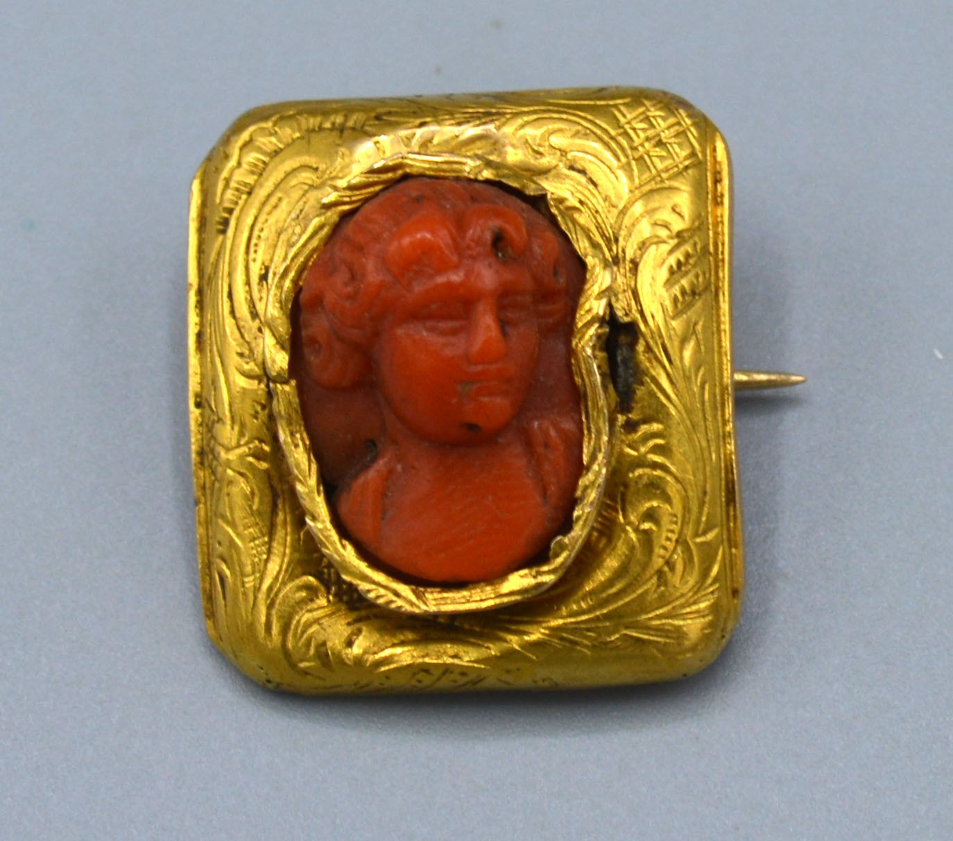 A Small Rectangular Brooch the carved coral centre in the form of a classical figure 2 x 1.5 cms