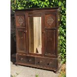 An Early 20th Century Oak Wardrobe with a moulded cornice above a central mirrored door flanked by