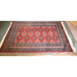 A Turkish Woollen Rug with an all over design upon a red blue and cream ground within multiple