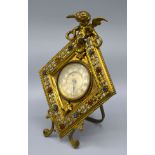 An Edwardian Brass Table Clock of lozenge form with putti surmount and set with paste stones, 20 cms