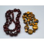 A Graduated Amber Bead Necklace together with a tiger's eye necklace