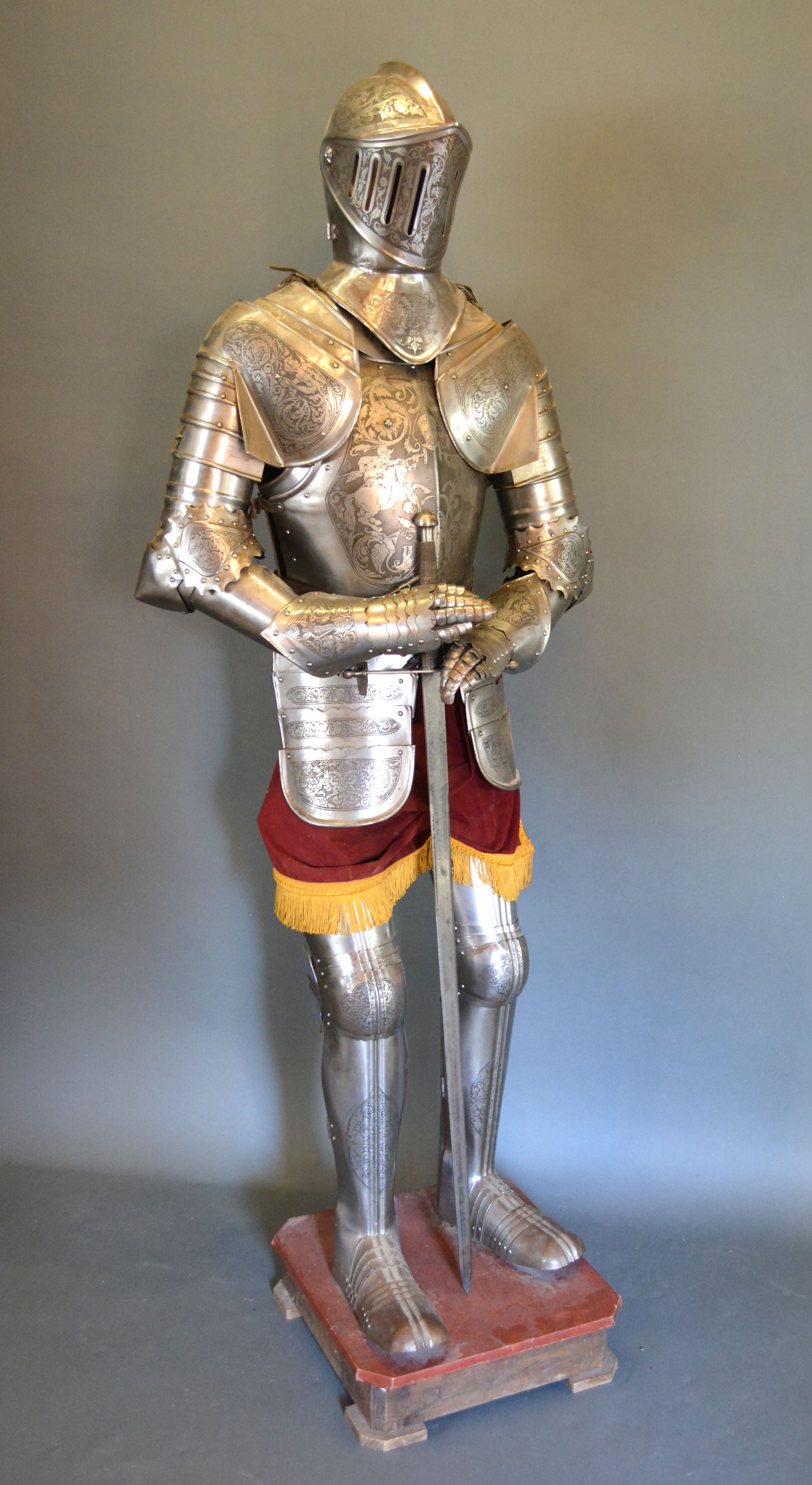 A 16th Century Style Suit of Armour complete with sword upon a wooden plinth 197 cms tall