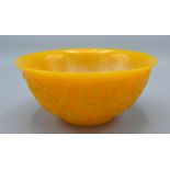 A Chinese Yellow Glass Bowl carved in relief with implements and scrolls, 15.5 cms diameter