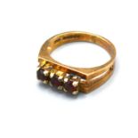 A 9ct Yellow Gold Dress Ring set with three garnets within a pierced setting, 3.3 gms Size K