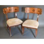 A Pair of Regency Side Chairs each with a stuff over seat raised upon sabre legs with brass caps and