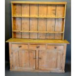 A Pine Dresser, the boarded shelf back above three drawers and two cupboard doors raised upon a