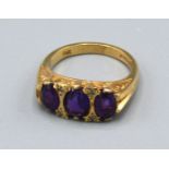 A 9ct. Gold Dress Ring set three amethysts interspaced with diamonds within a pierced scroll