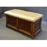 A Victorian Walnut Ottoman, the hinged padded seat above pierced fretwork and fabric panels and with