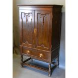 An Arts and Crafts Oak Side Cabinet by The Arts And Crafts Ltd. the moulded cornice above two