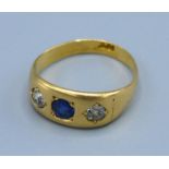 An 18ct gold three stone ring, with a central sapphire flanked by diamonds, ring size M, 4gms