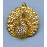 An 18ct gold pendant brooch in the form of a Peacock set with pearls and ruby eye. 3.5cms x 3cms,