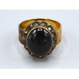 An 18ct. Gold Ring set with a cabochon oval garnet surrounded by diamonds, ring size K, 7.1 gms.