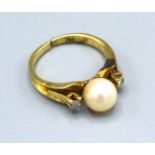 A 14ct. Gold Ring set with a central pearl flanked by diamonds, ring size J, 3.7 gms.