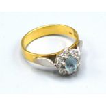 An 18ct. Gold Aquamarine and Diamond Cluster Ring with a central aquamarine surrounded by diamonds