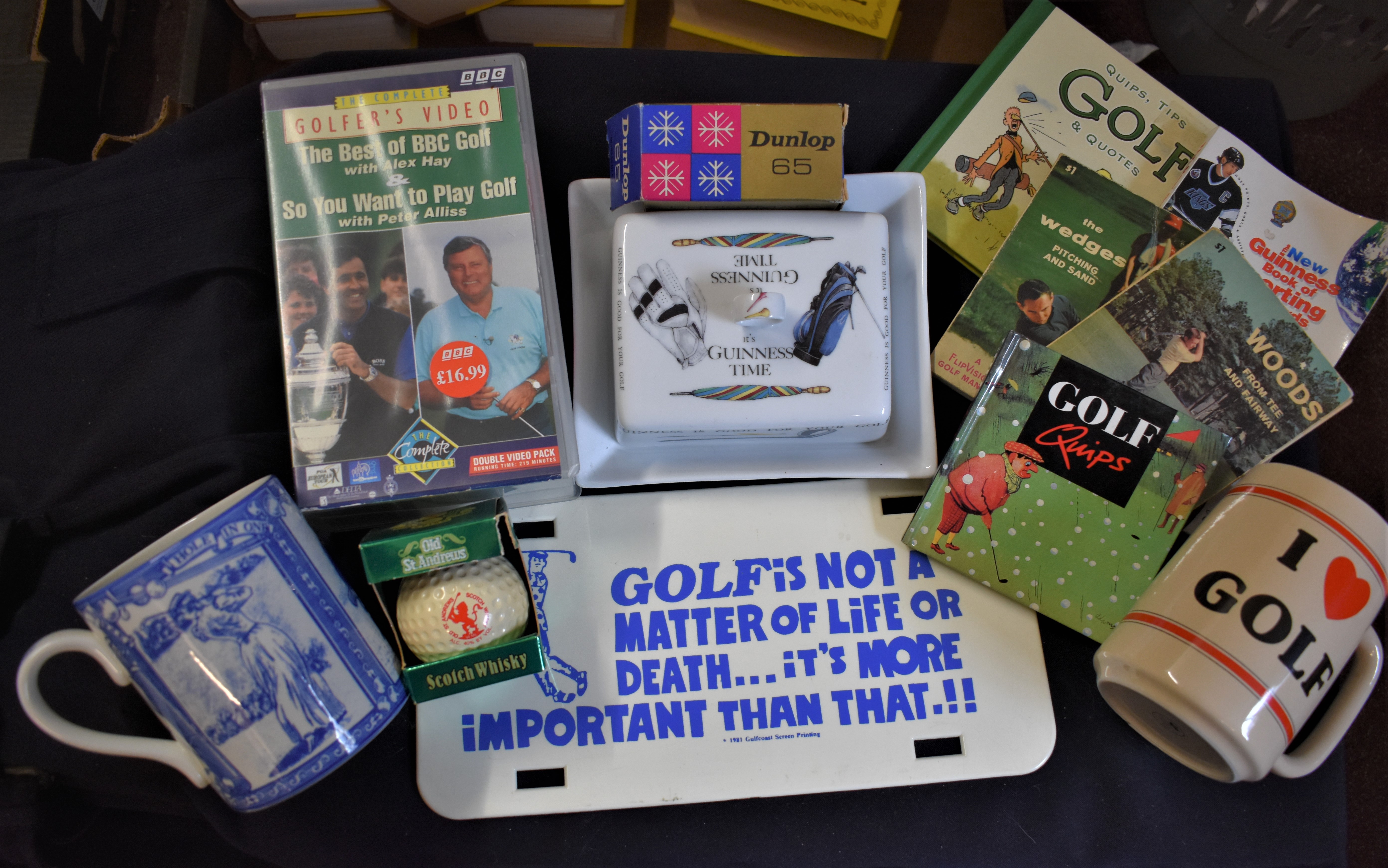 A good selection of vintage golfing memorabilia mugs including a Guinness Butter plate, books, VHS