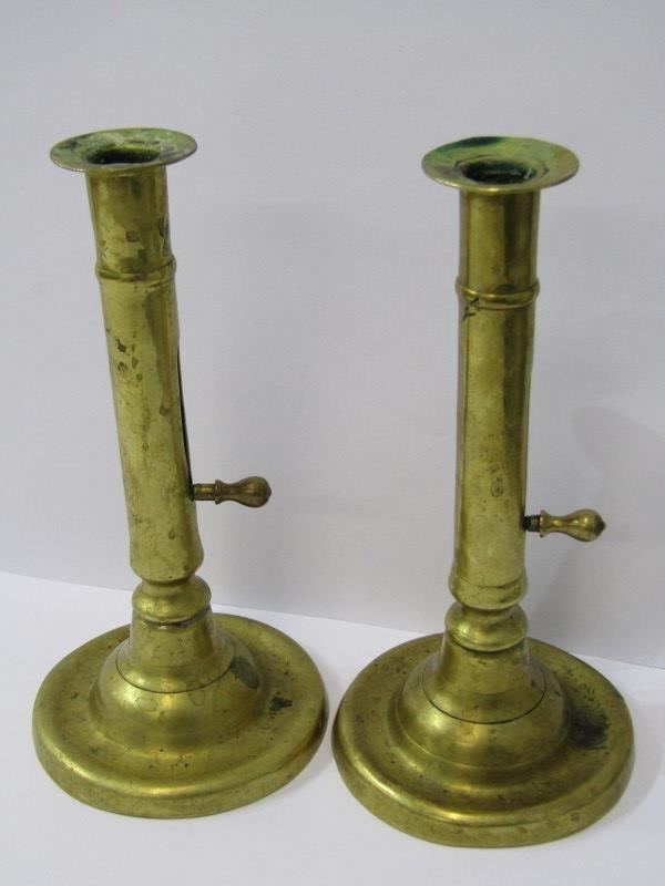 GEORGIAN BRASSWARE, A pair of circular base brass ejector candle sticks, 7" height