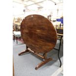 A continental oval walnut tilt top trestle end table.