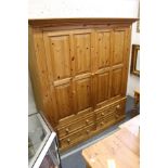 A modern pine wardrobe with two large doors above four drawers.