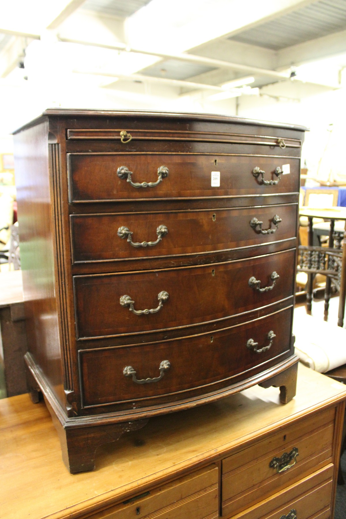 A George III style mahogany bow front four drawer chest with brushing slide.