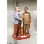 A Russian pottery group of two figures standing shaking hands.