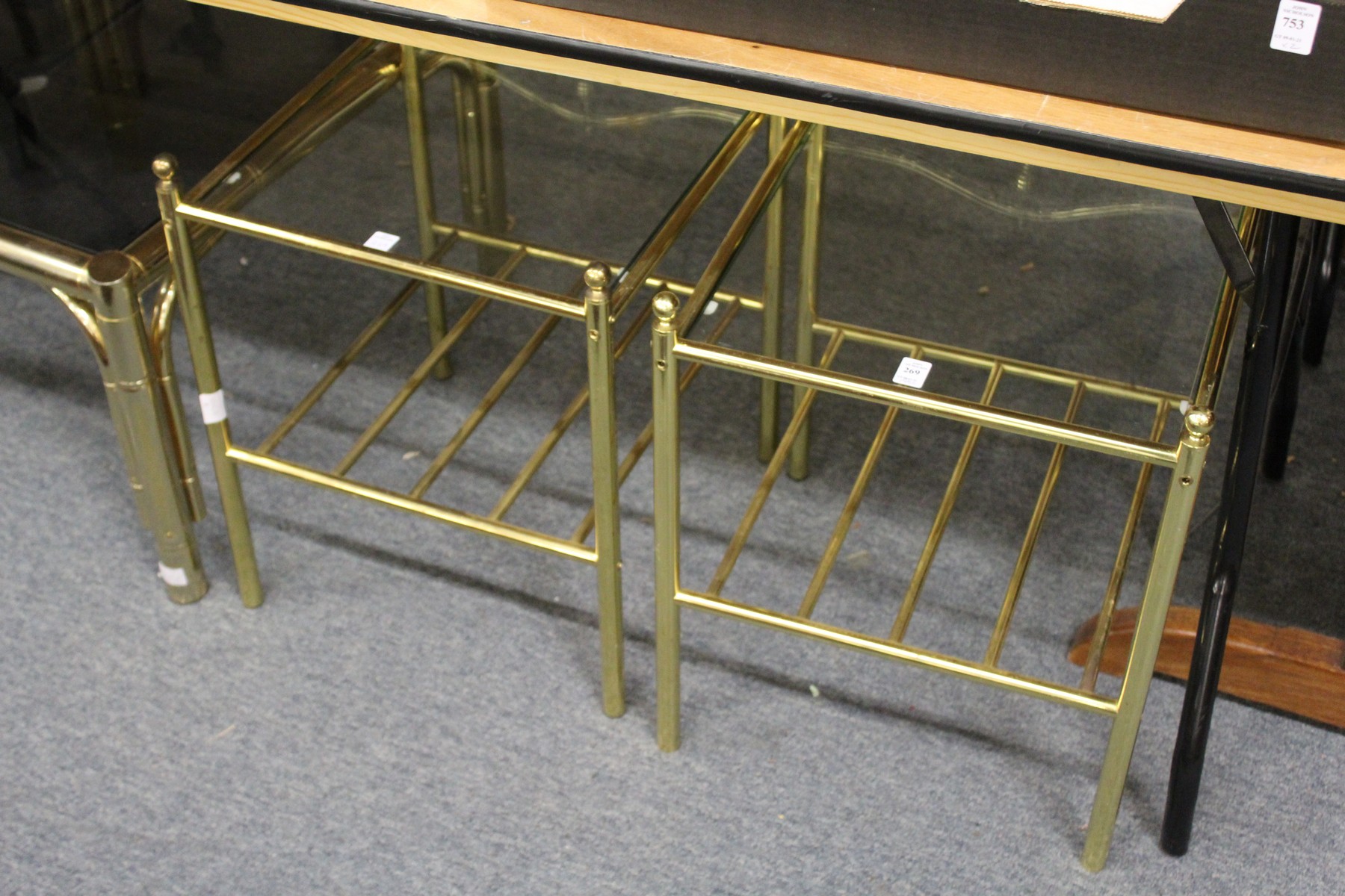 A pair of stylish brass framed two tier glass topped lamp tables.