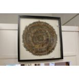 A circular feather picture, framed and glazed.