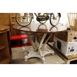 A circular dining table with polished hardwood top and decorative painted base.