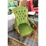 A Victorian walnut framed armchair with button upholstered back.