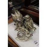 A silvered model of a pair of birds and a similar snail.