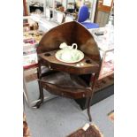 A mahogany corner wash stand complete with porcelain jug and bowl.