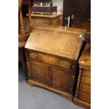A George III oak bureau with a drop flap, over a single drawer and pair of cupboard doors.